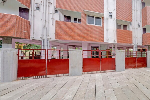 A multi-story building with a red brick facade, white exterior walls, and a gated entrance. - Deluxe tad Homes (Sriperumbudur)