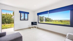 A spacious room with a large window, a flat-screen TV, and a white cabinet.