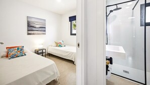 A hotel room with two beds, a shower area, and a painting on the wall.