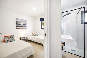 A hotel room with two beds, a shower area, and a painting on the wall.