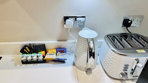 Une cuisine équipée d’une machine à café, d’un grille-pain et d’une étagère contenant des produits alimentaires.