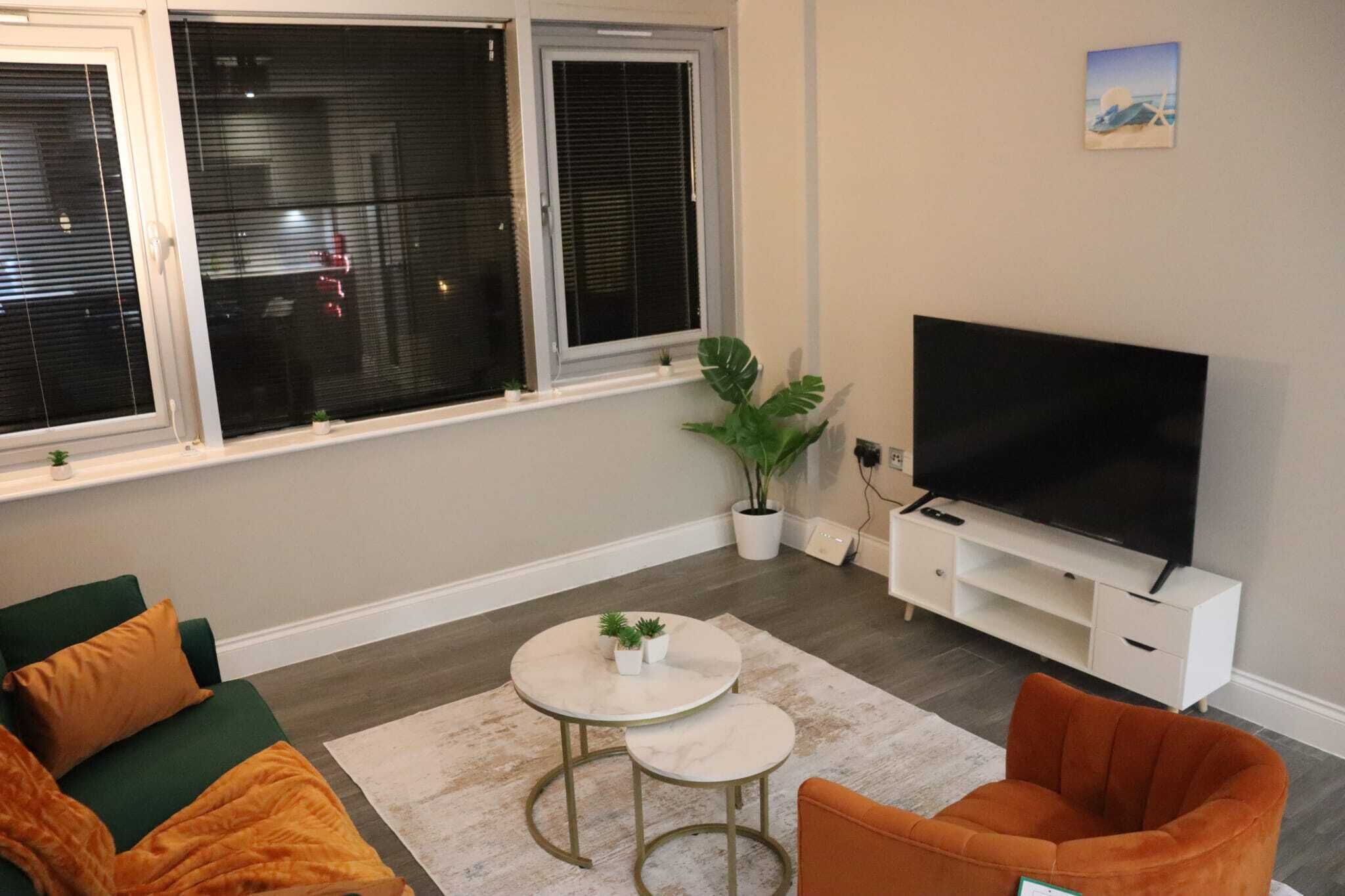 A living room with a TV, two sofas, a coffee table, and a plant.