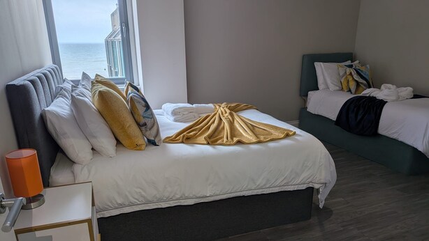 Une chambre d’hôtel avec un lit, une vue sur la mer, une table de chevet et une fenêtre.