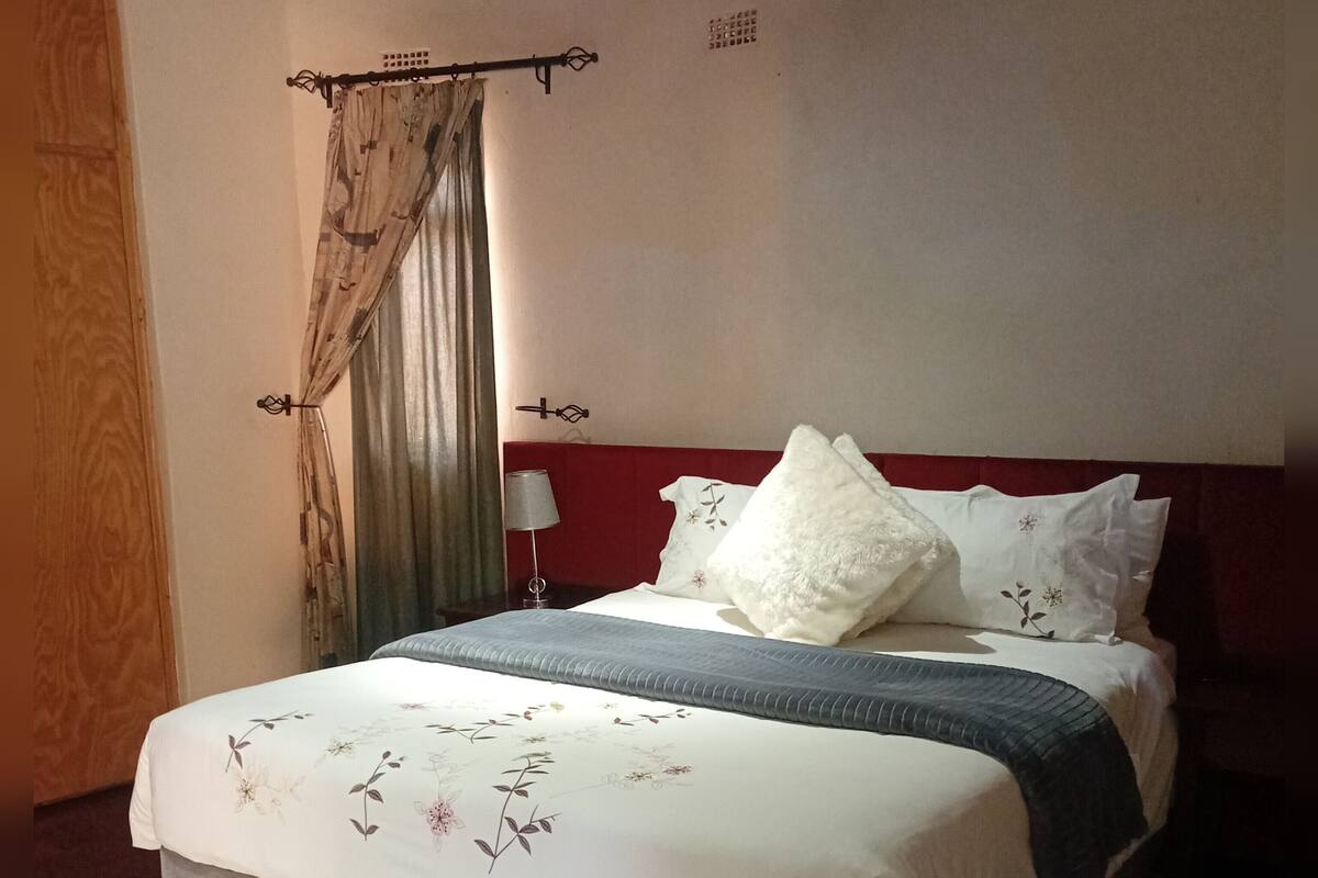 A bed with a floral bedspread, a white pillow, and a grey blanket.
