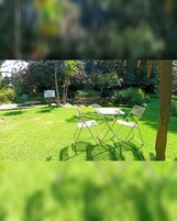 Un espacio al aire libre cubierto de césped con dos sillas plegables blancas y un cartel que dice 'Green Oasis'.