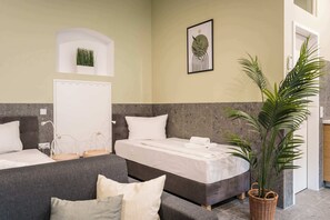 A hotel room with a bed, a sofa, a potted plant, and a wall-mounted artwork. - Modern Living in Friedrichshain by Sabine (Berlin)