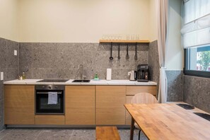 A modern kitchen with a built-in oven, a sink, and a wooden dining table. - Modern Living in Friedrichshain by Sabine (Berlin)