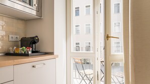 Eine Küche mit Kaffeemaschine, einem Fenster und Blick auf den Außenbalkon.