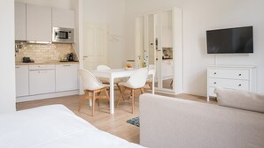 Eine moderne Küche mit weißen Schränken, einer Mikrowelle und einem Essbereich mit Tisch und Stühlen.