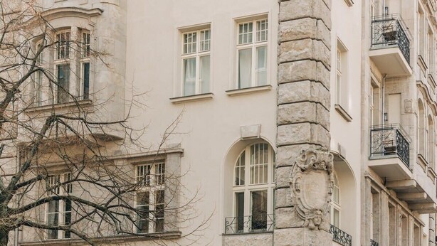 Ein mehrstöckiges Gebäude mit Bogenfenstern und Steindetails, das einen historischen oder klassischen Architekturstil vermittelt.