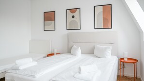 Ein Hotelzimmer mit zwei Betten, einem großen Fenster und drei gerahmten Kunstwerken an der Wand.
