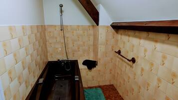 Une salle de bain avec une baignoire, un petit lavabo et une douche.