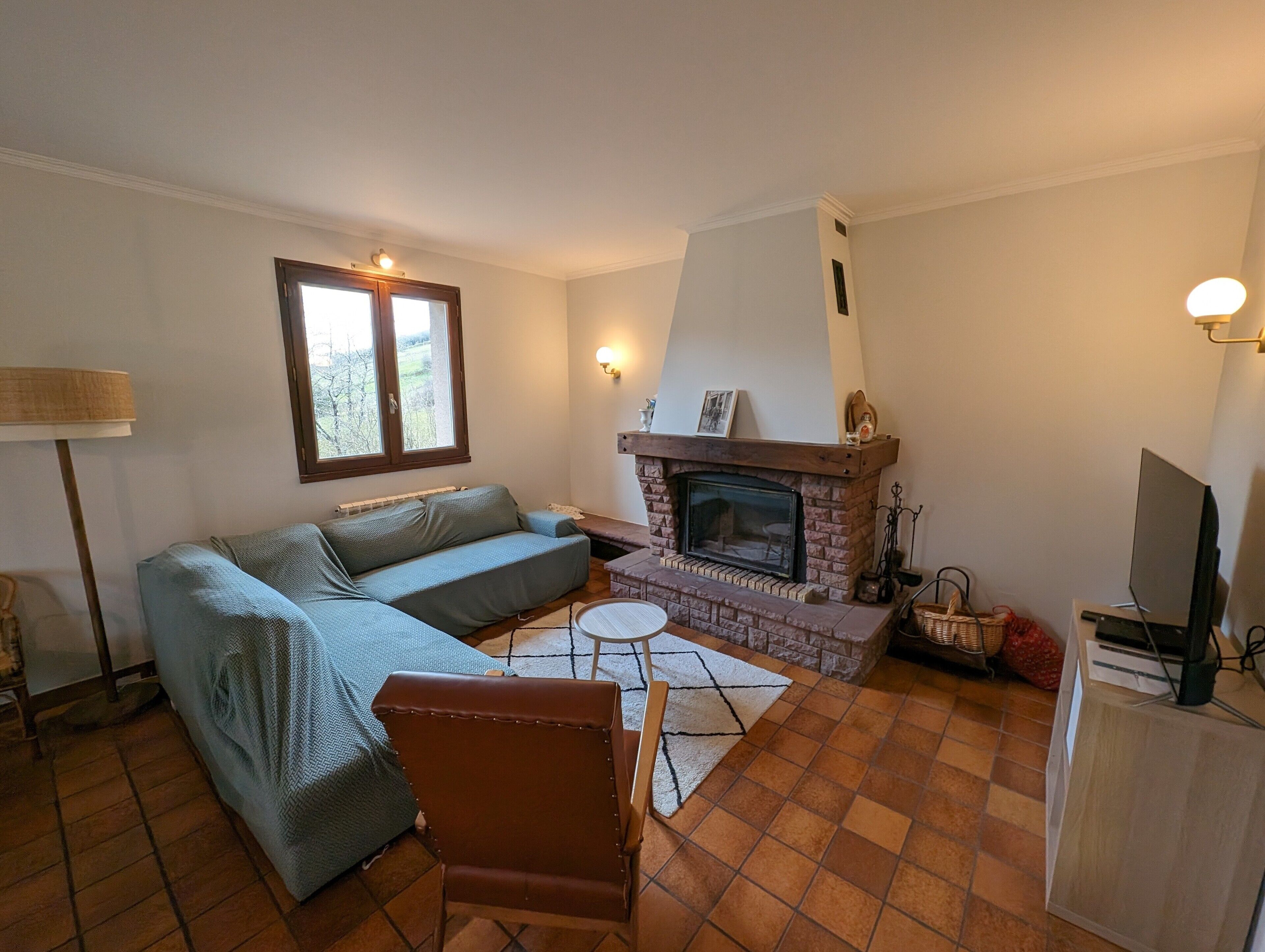 A living room with a sofa, a fireplace, a television, and a lamp.