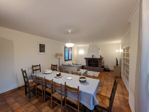 A dining area with a table set for four, a fireplace, and a sofa in the background. - Spacious Charming House for 12 – Vineyard Views & Tranquility for Families/Friends/Sports Groups (Clairvaux-d'Aveyron)