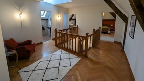 Un loft spacieux avec un escalier en bois, une lucarne et une vue sur la cuisine.
