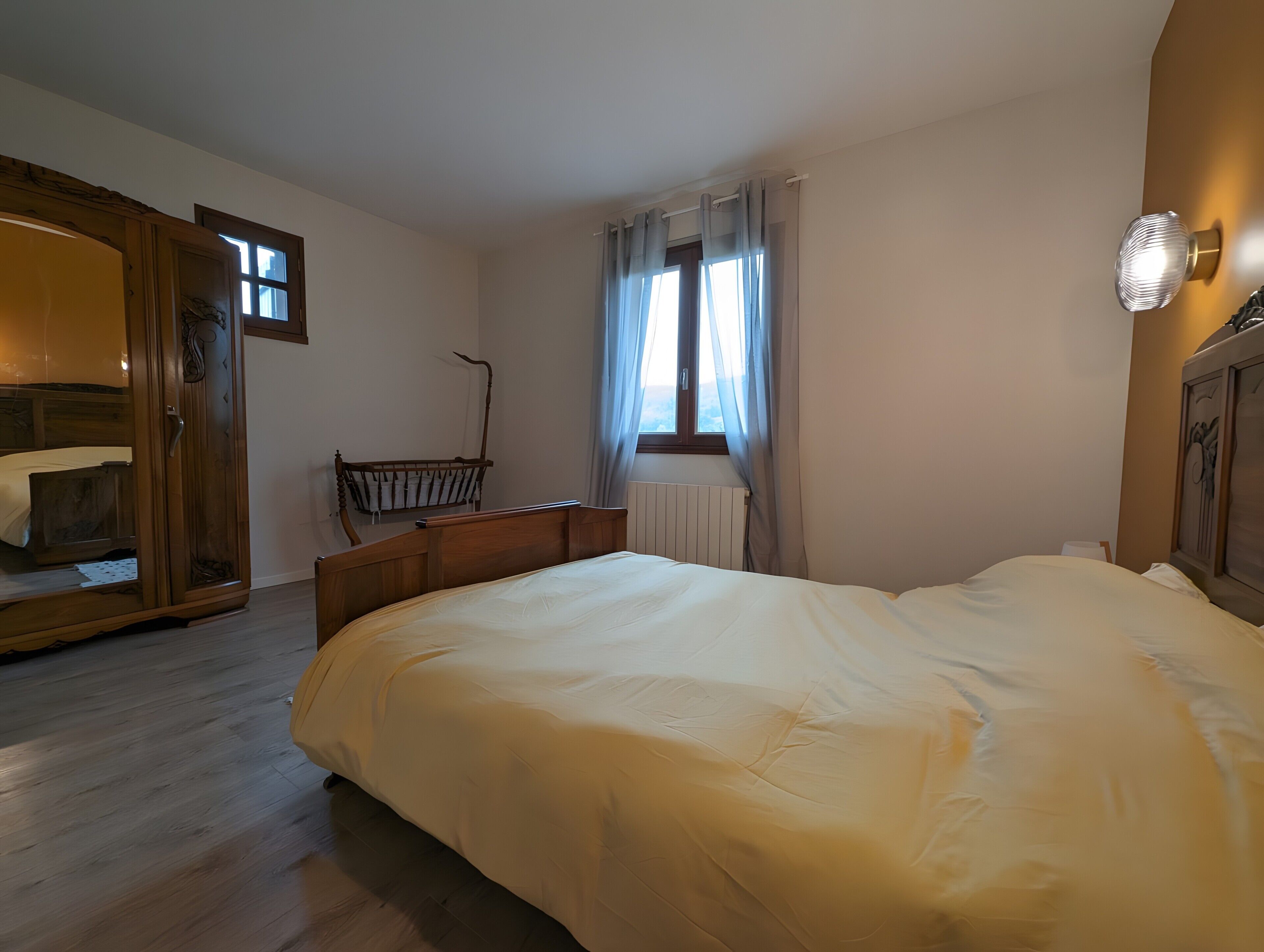 Un dormitorio con una cama grande, un armario de madera, un escritorio y una ventana con cortinas.