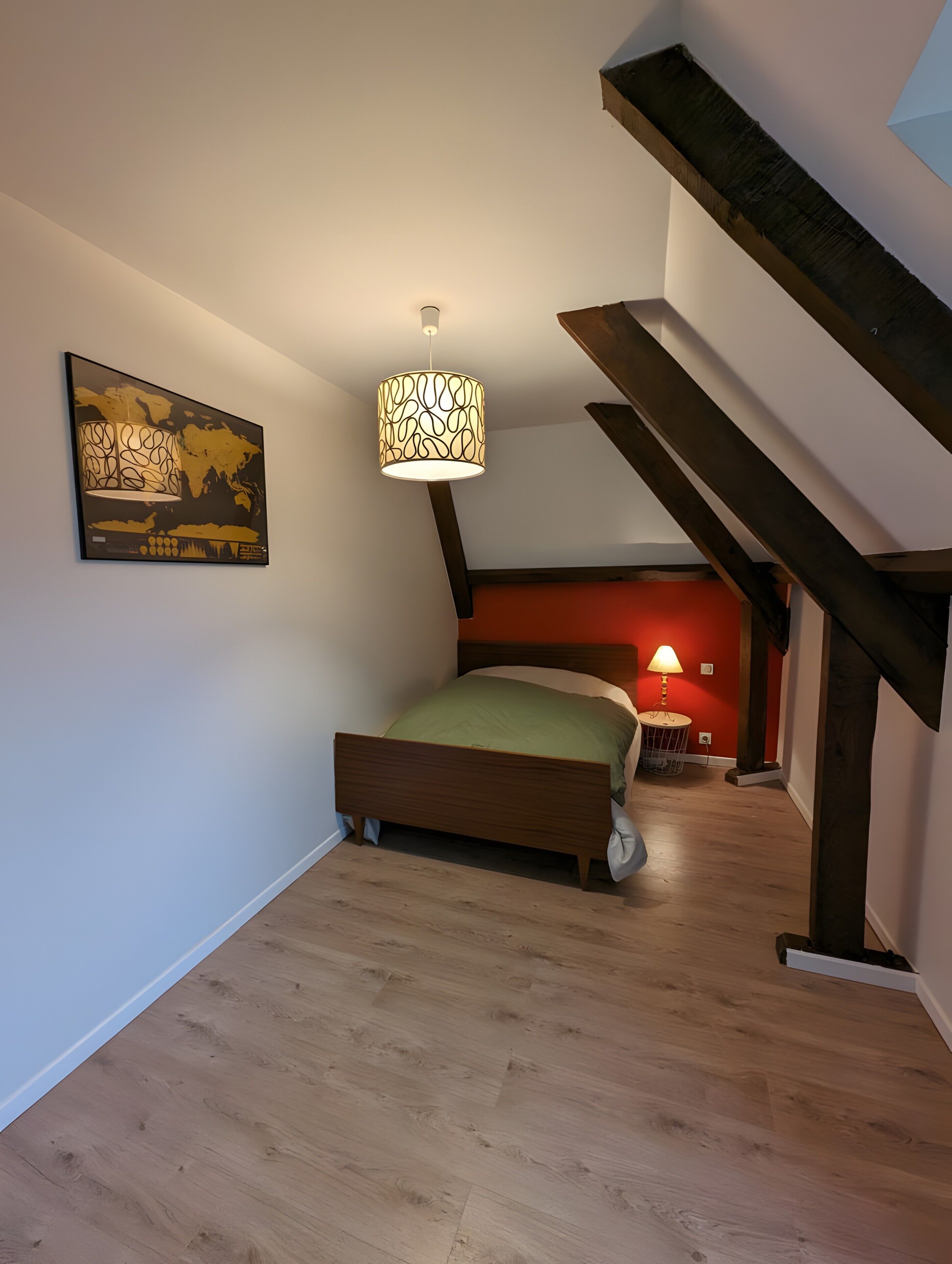 Een slaapkamer met een bed, een hanglamp, een schilderij en een trap.