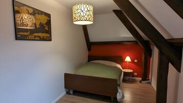 Een slaapkamer met een bed, een hanglamp, een schilderij en een trap.