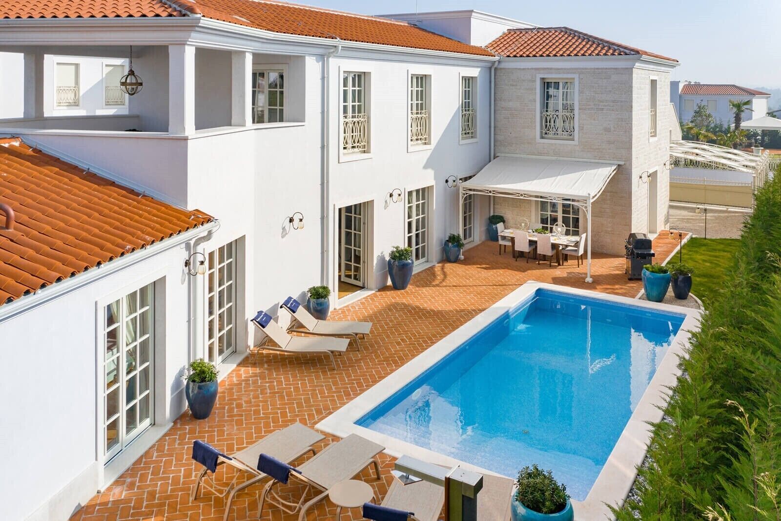 A two-story house with a swimming pool, outdoor seating, and a covered patio area.