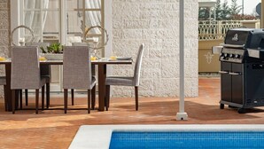A poolside area with a dining table, chairs, a grill, and a view of a pool. - Villa Fiordaliso – Luxury villa for up to 6 guests with private pool in peaceful Mediterranean surroundings. (Vabriga)