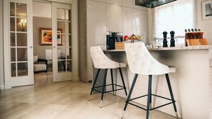 A modern kitchen with two bar stools, a countertop with kitchen tools, and a door leading to a dining area. - Villa Fiordaliso – Luxury villa for up to 6 guests with private pool in peaceful Mediterranean surroundings. (Vabriga)