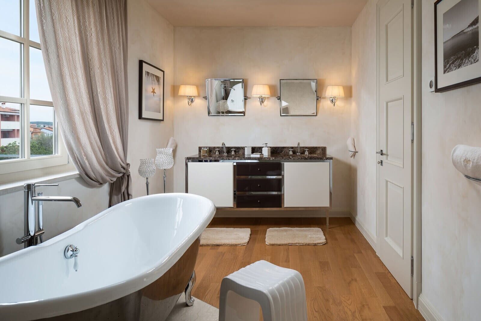 A modern bathroom with a freestanding bathtub, a vanity with a mirror, and two wall-mounted lights.