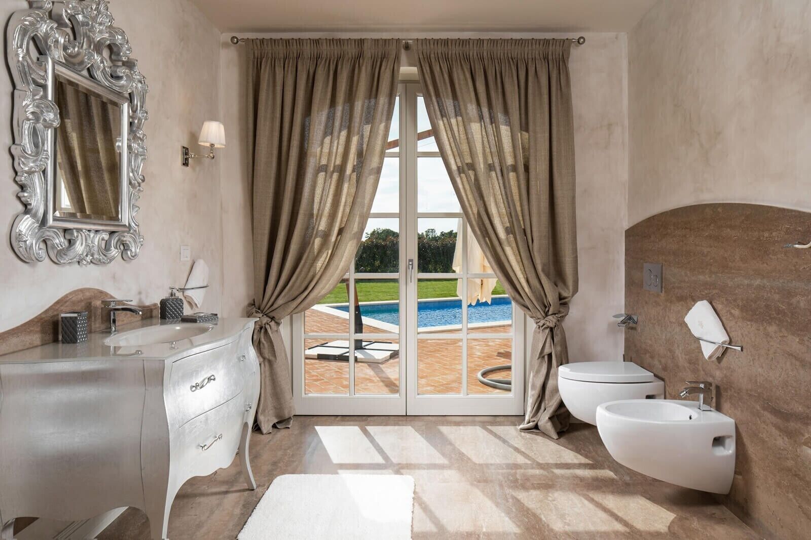 A bathroom with a large window, a sink, a toilet, and a mirror.