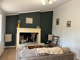 Una sala de estar con chimenea, un sofá, una silla y una lámpara.