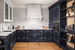 Eine moderne Küche mit dunklen Schränken, einer weißen Arbeitsplatte und einem Holzboden.