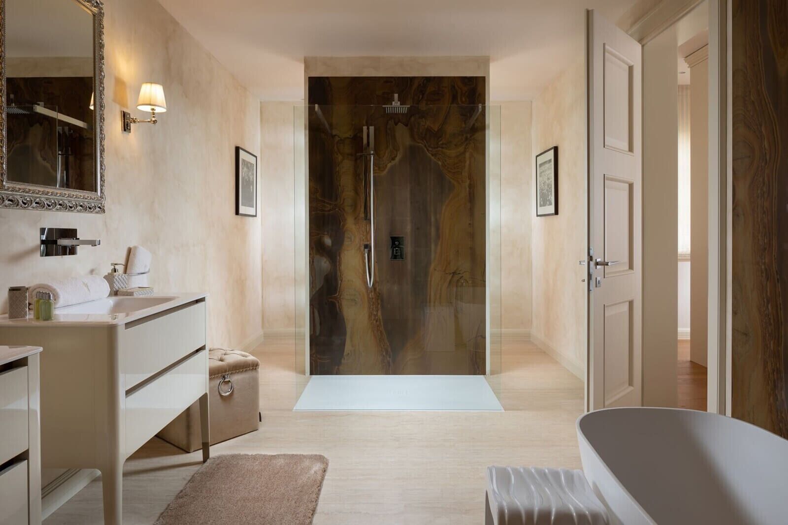 A modern bathroom with a glass shower, a bathtub, a vanity with a mirror, and a bench.