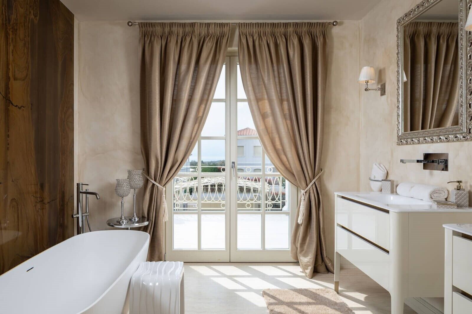 A bathroom with a bathtub, a sink, a mirror, and a view through a glass door.