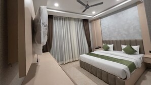 Una camera d'albergo con un letto, un ventilatore a soffitto, un comodino e una finestra con tende.