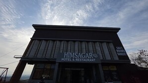 Un edificio con un cartello che riporta 'HIMSAGAR HOTEL & RESTAURANT' e 'CAFE ROOMS BANQUE', che indica un albergo e ristorante.