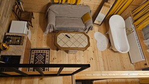 A room with a bed, a small table, a bathtub, a radiator, and a window. - Mood villa kazbegi is city centre of Stepantsminda, with mountimes view. For you (Stepantsminda)