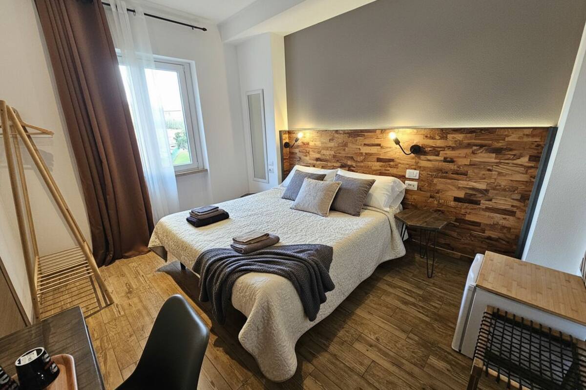 Ein Schlafzimmer mit einem Bett, einem Nachttisch und einem Fenster mit Vorhängen.