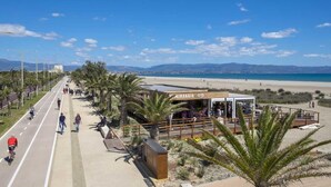 A coastal road with a beachside restaurant named 'AIRAGGIO' and a clear view of the beach and mountains in the distance. - ARYA Cagliari (Cagliari)