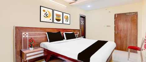 A bedroom with a bed, a nightstand, a red chair, a ceiling fan, and framed artwork on the wall.