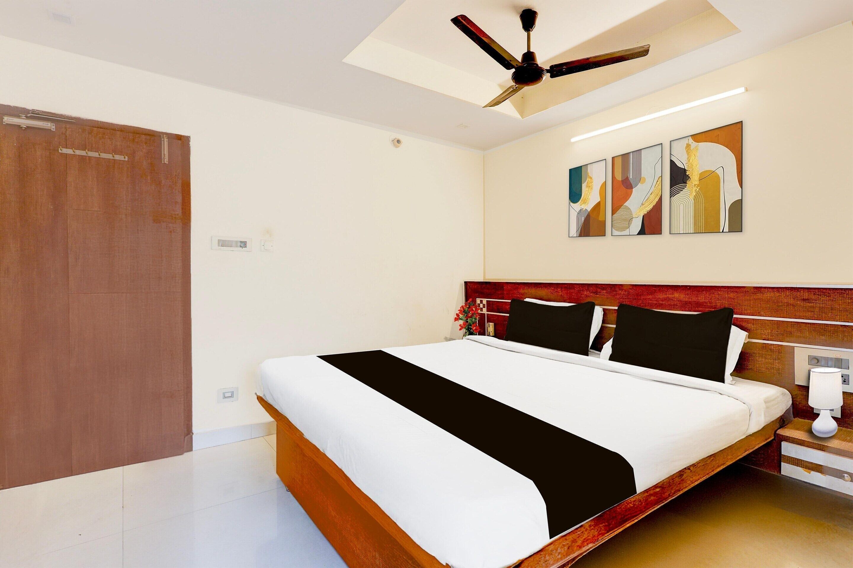 A bedroom with a bed, a ceiling fan, a nightstand, and a wall-mounted artwork.