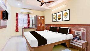 A bedroom with a bed, bedside table, wardrobe, ceiling fan, artwork, and a window with curtains.
