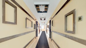 A long, narrow hotel corridor with mirrored walls and a black carpet.