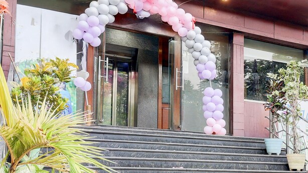A building entrance with a marble staircase, a glass door, and a decorative arch of balloons.