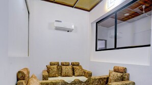A room with a sofa set, a large window, and an air conditioning unit. - Deluxe Seven Hills Aurangabad (Chhatrapati Sambhajinagar)