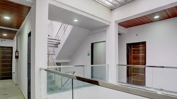 A modern interior with a glass railing, a staircase, and a wooden door. - Deluxe Seven Hills Aurangabad (Chhatrapati Sambhajinagar)