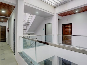 A modern interior with a glass railing, a staircase, and a wooden door.