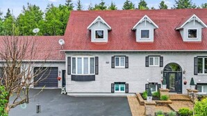 Een tweelaags huis met een rood dak, witte omlijsting en een voortuin met een deur en ramen.