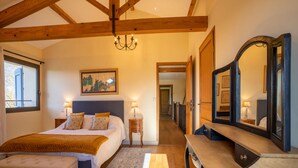 Un dormitorio con cama, mesitas de noche, cómoda, espejo y candelabro.