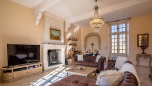 Una sala de estar con chimenea, televisor y candelabro.