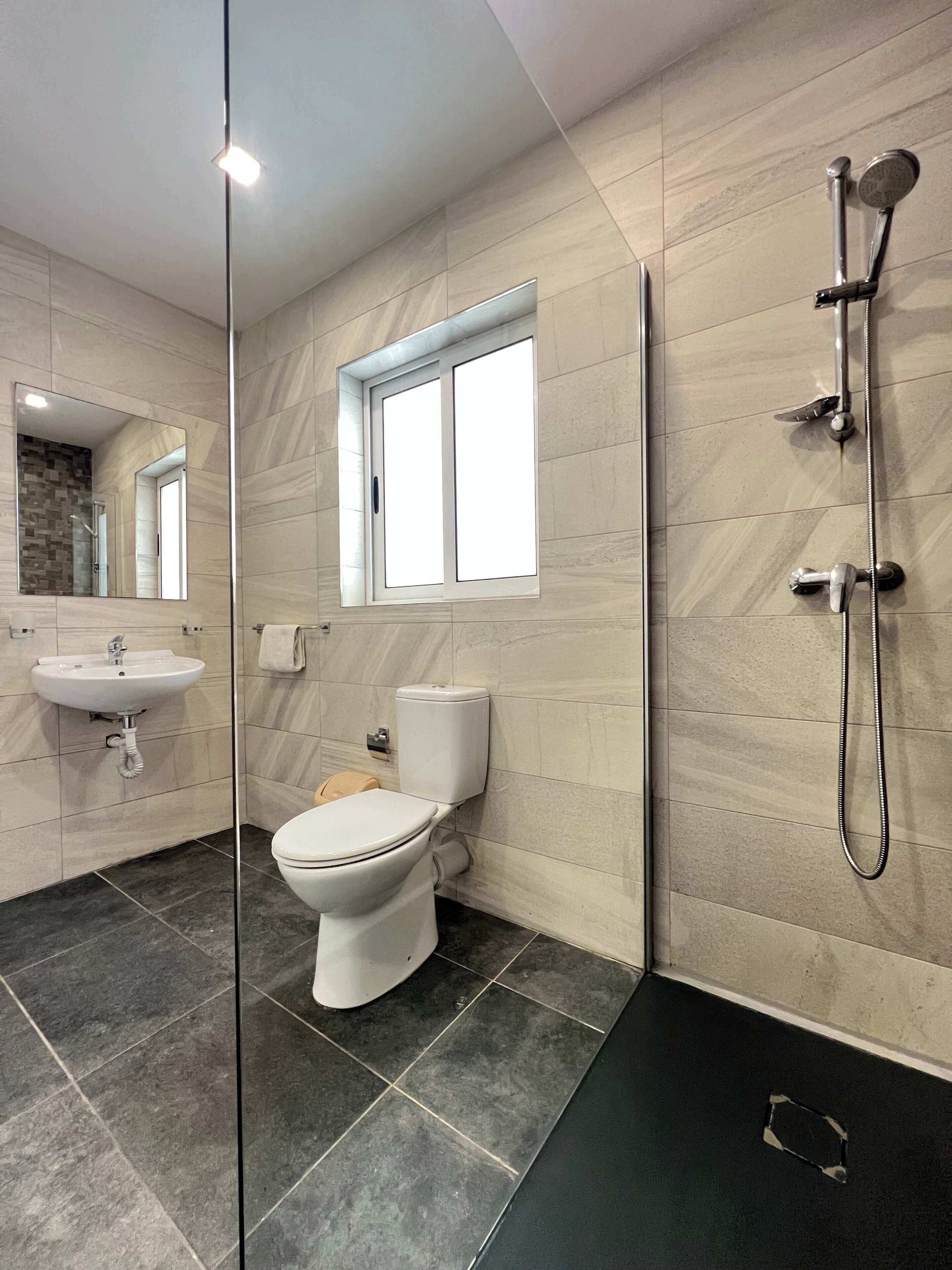 A modern bathroom with a toilet, sink, and shower.