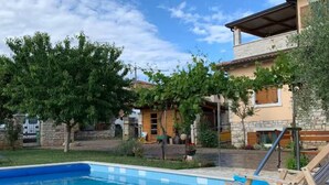 Ein Pool mit einer gefliesten Kante, eine Holzliege und eine Steinterrasse.