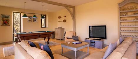 A living room with a pool table, a sofa, a television, and a bookshelf.